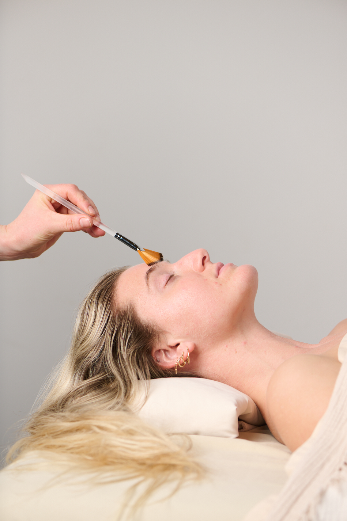 Numbing cream being applied to a patient's face before microneedling treatment at Point Acupuncture in Portland, Maine